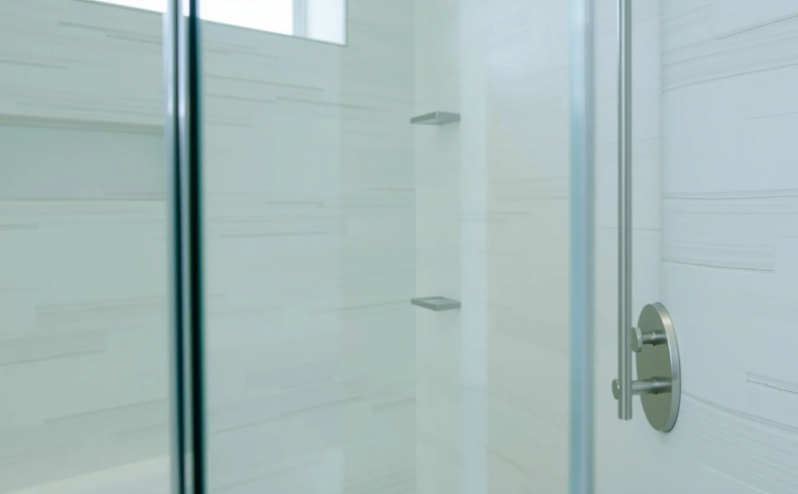 A frameless glass, curbless walk-in shower completed by Haven in a Kendale Lakes home — featuring large-format tile, a linear drain, and a ceiling-mounted rainfall head. Haven bathrooms in Kendall, FL — Schluter waterproofing membrane applied to shower walls before tiling