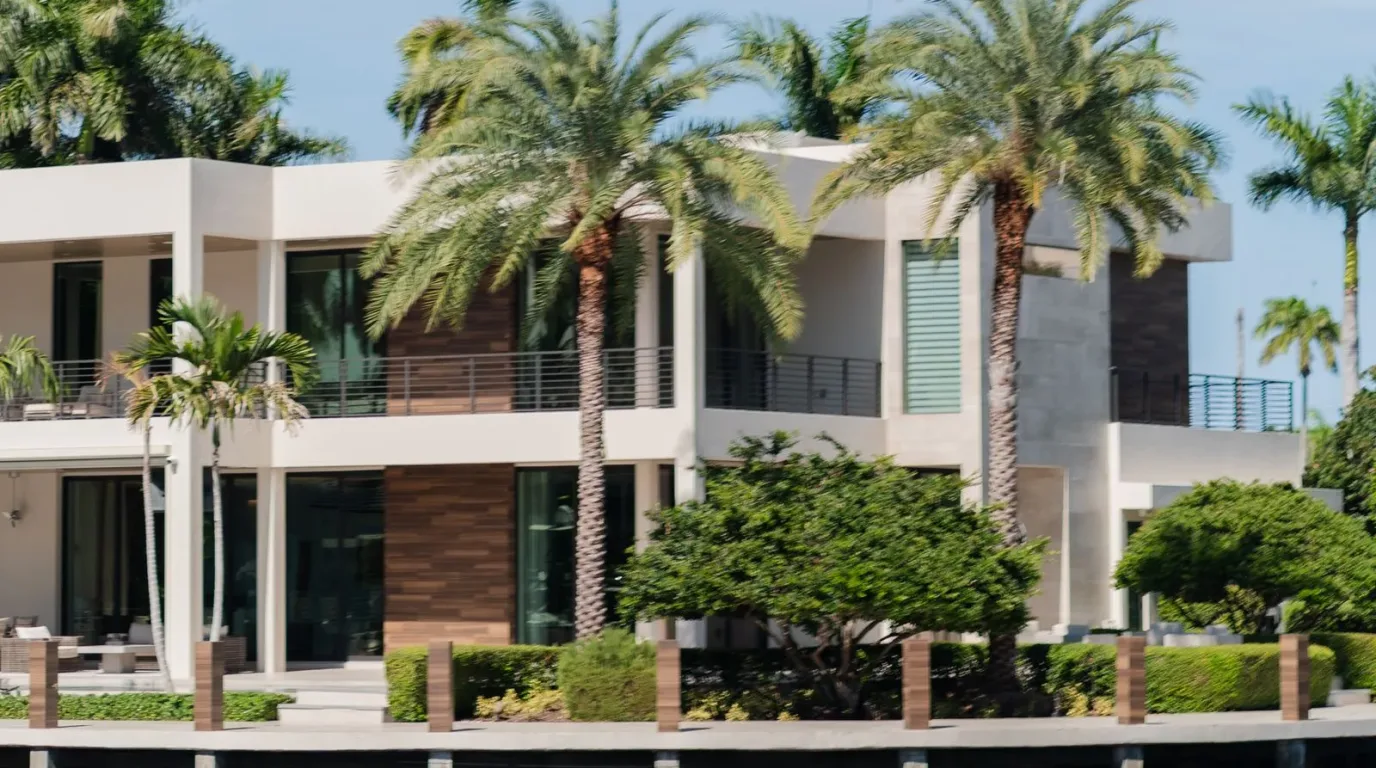 Modern waterfront South Florida home with large glass openings and palm trees